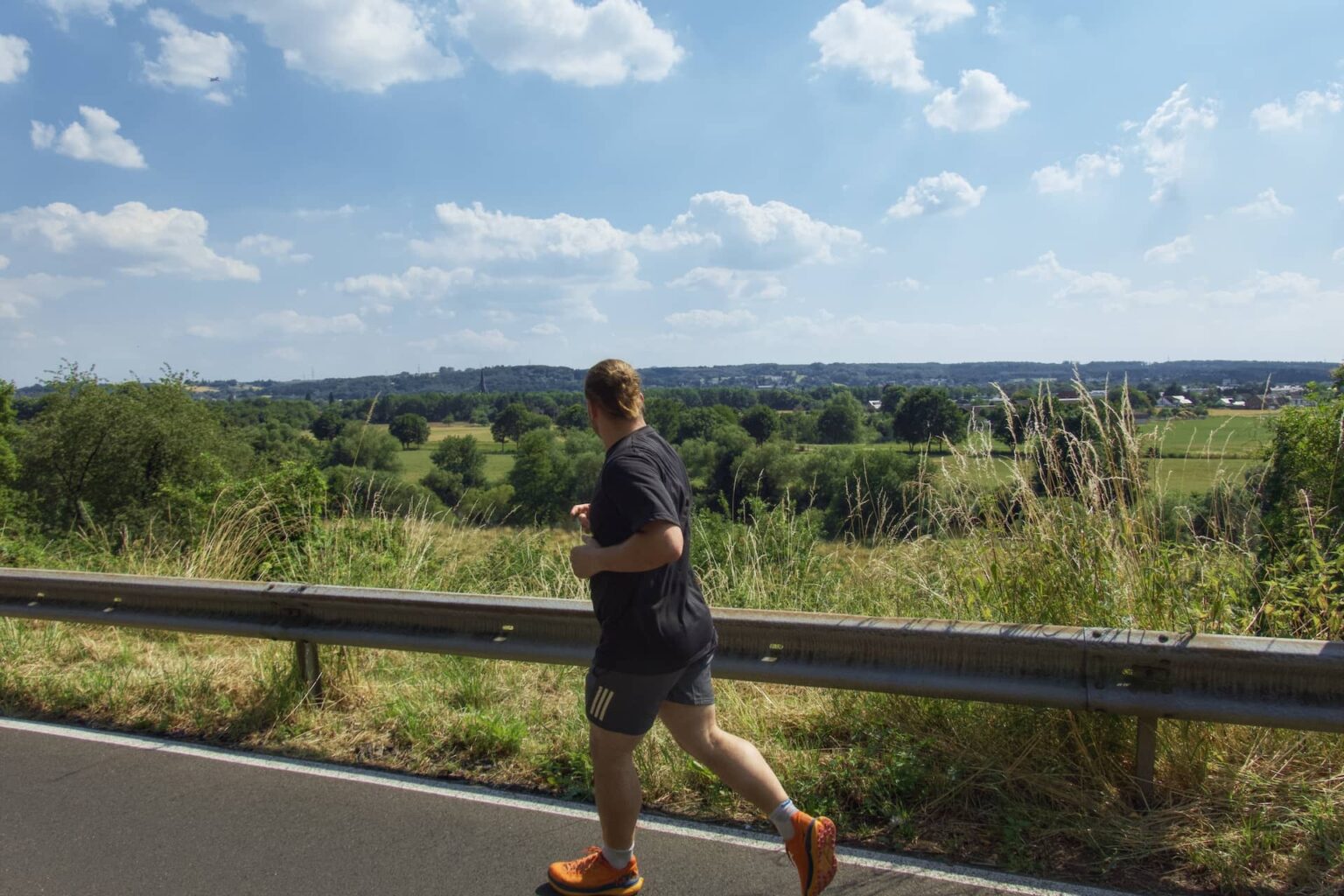 Läufer nimmt am Europalauf Hennef teil und joggt eine Straße mit Ausblick entlang.
